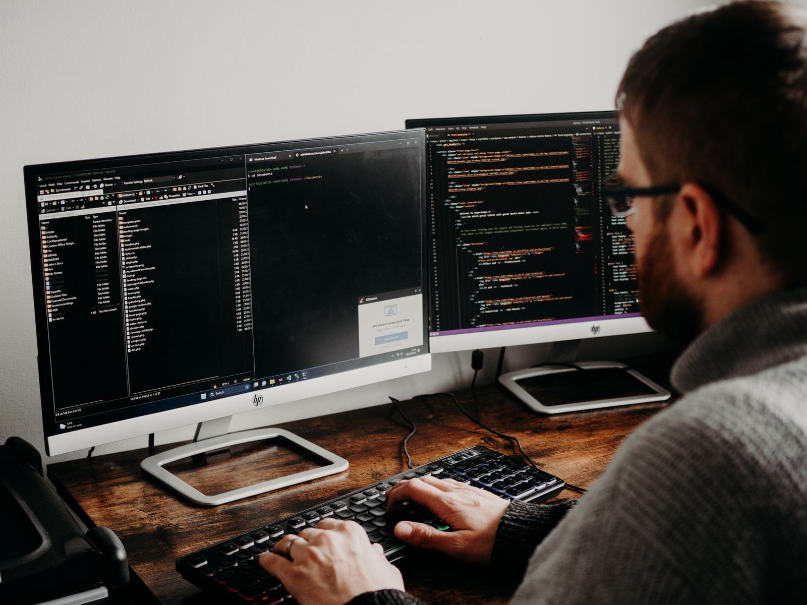 Dual monitor workstation displaying code and text editor interfaces.