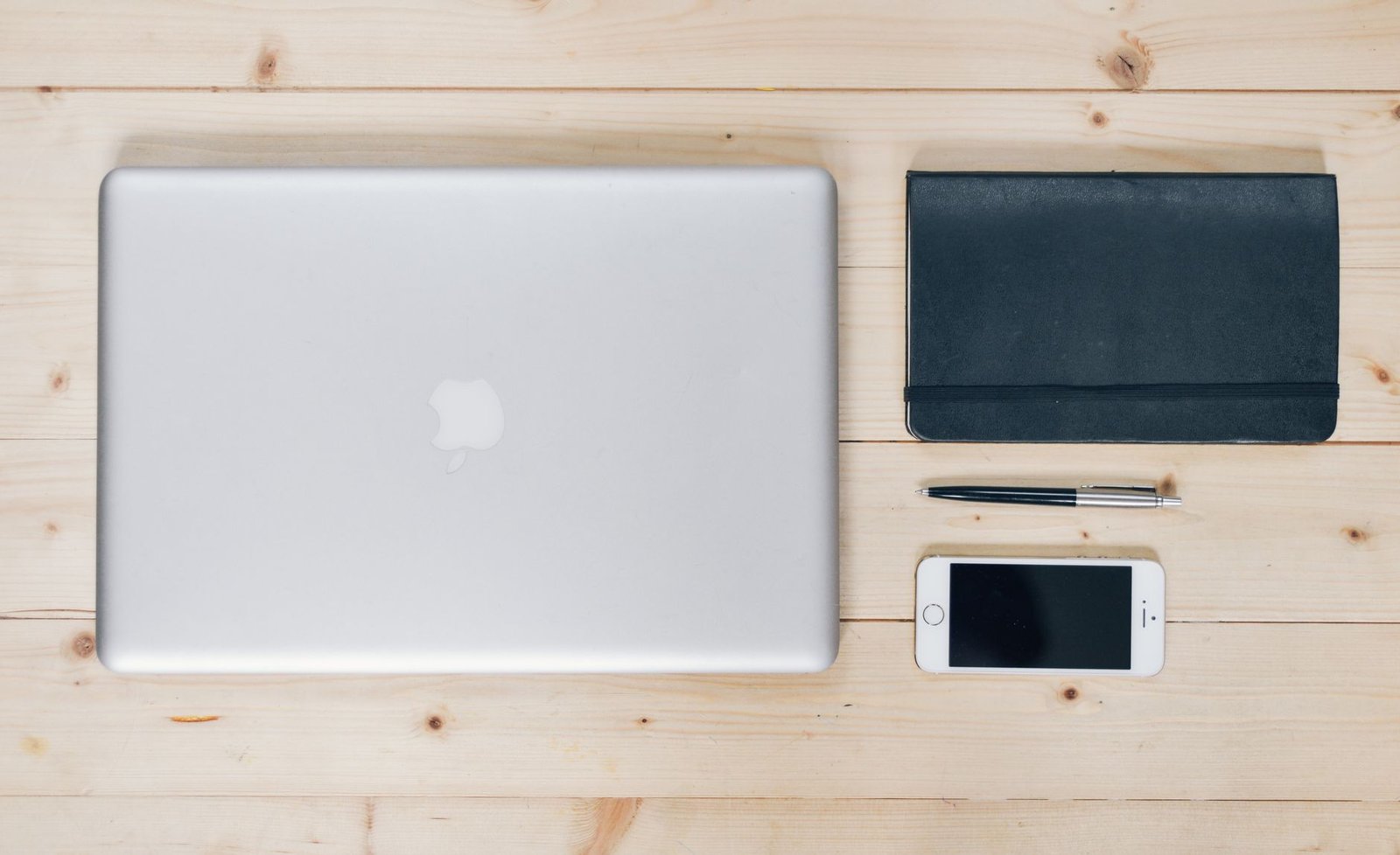 Clean white desktop with a single aluminum laptop and focused lighting.