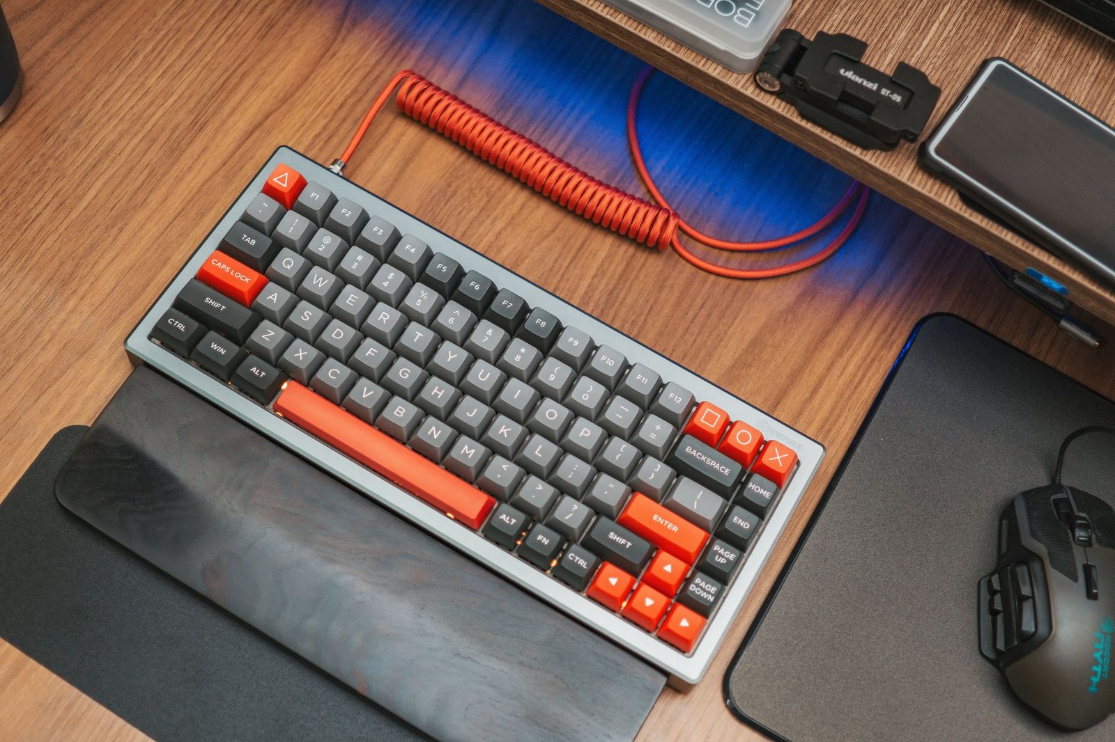 A clean modern desk setup featuring a multi-device wireless mechanical keyboard.