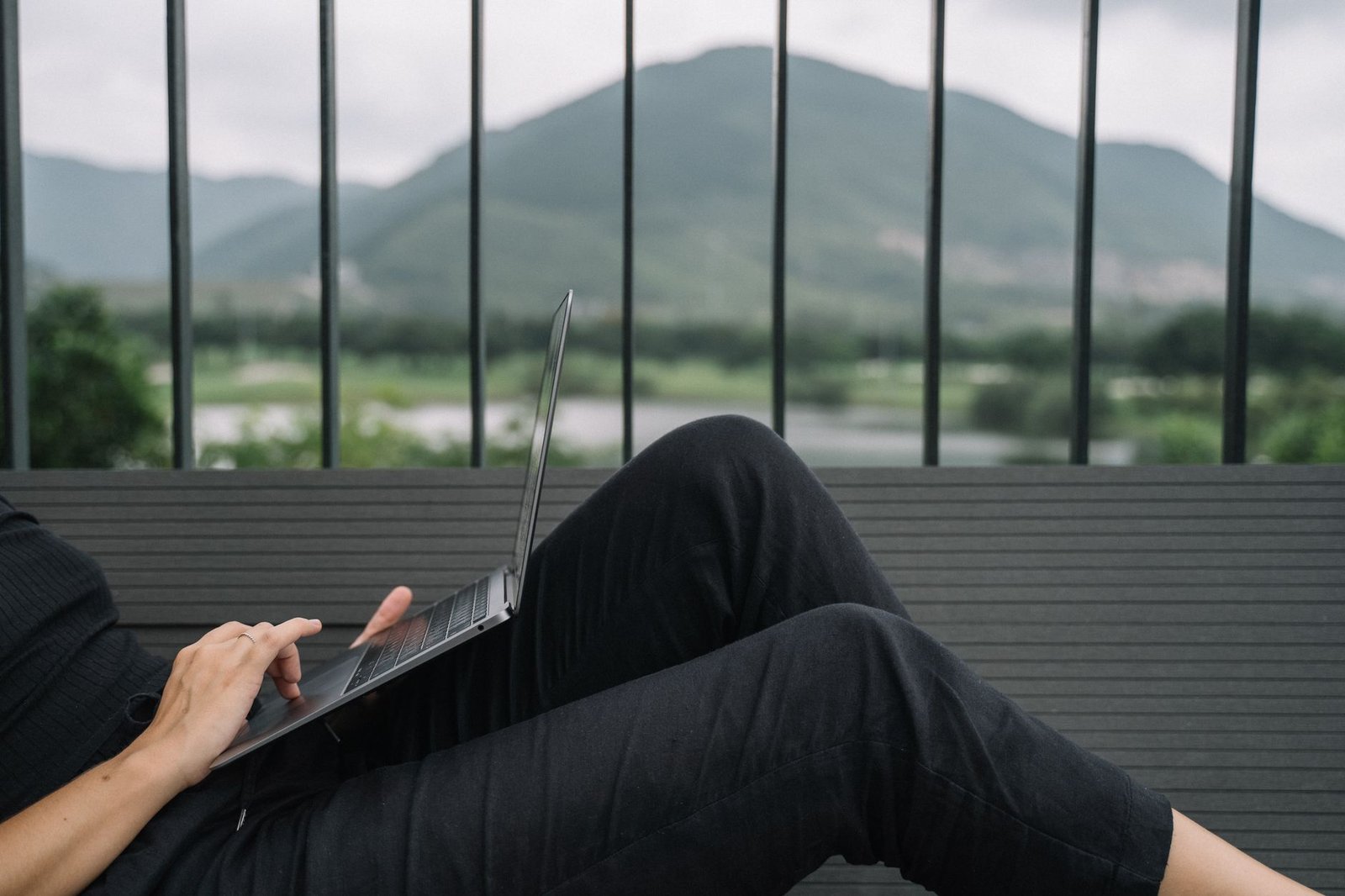 Professional typing on a sleek laptop keyboard in an outdoor setting.