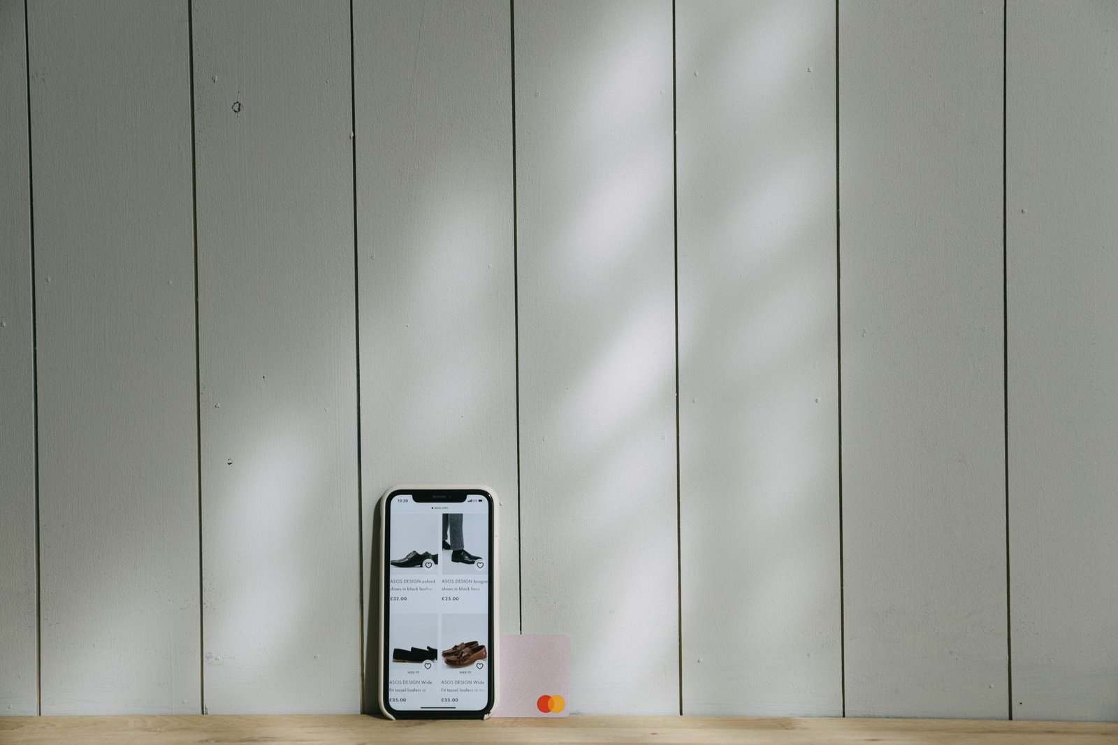 A sleek grey e-ink mobile device resting next to a white coffee cup.