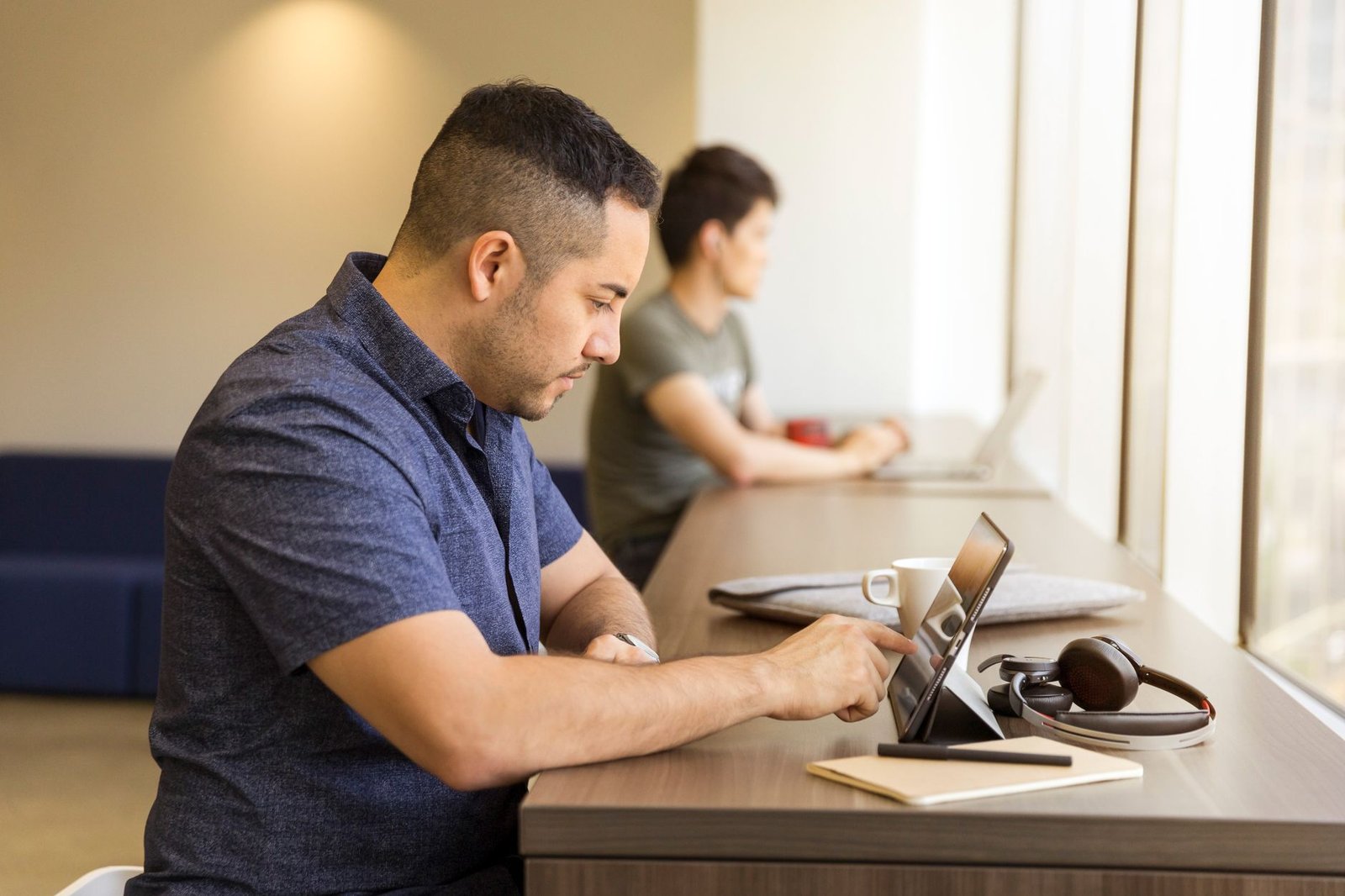 Professional focused on laptop screen in a modern workspace.