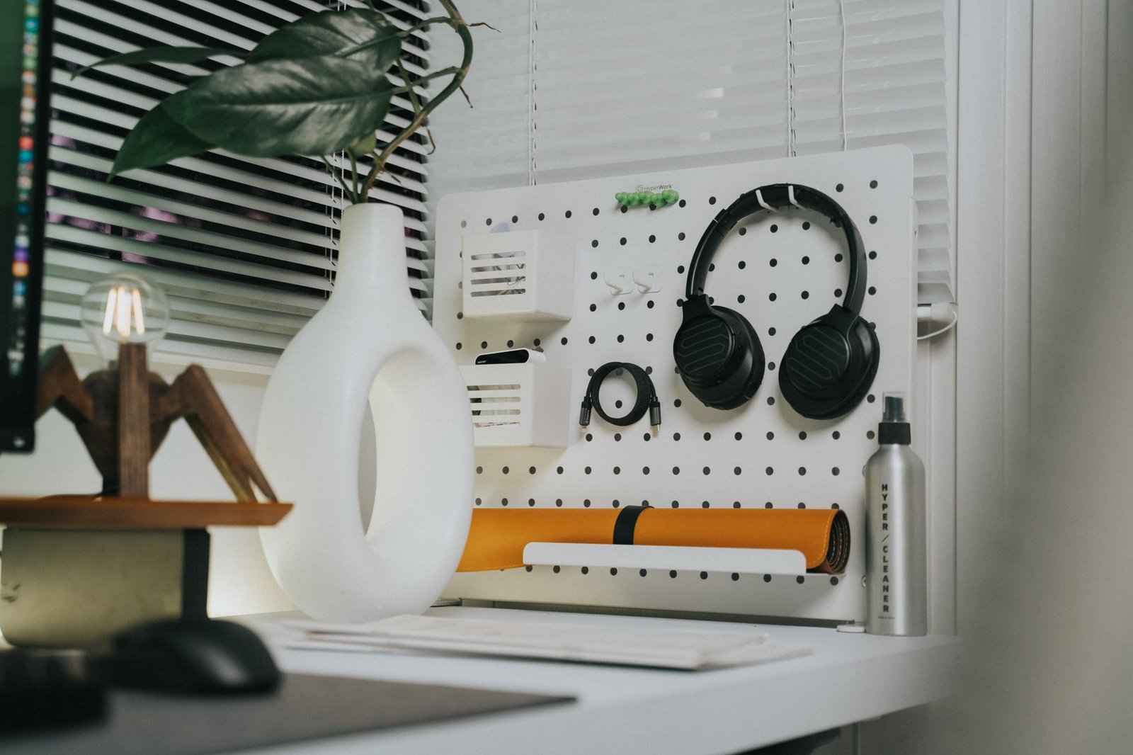 Sturdy aluminum headphone hook securely clamped to the side of a modern wooden desk.