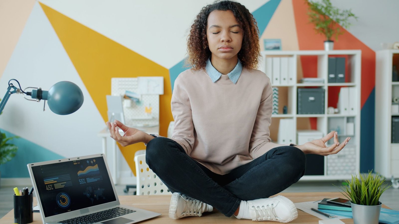 Professional woman practicing deep breathing exercises at her modern workstation.