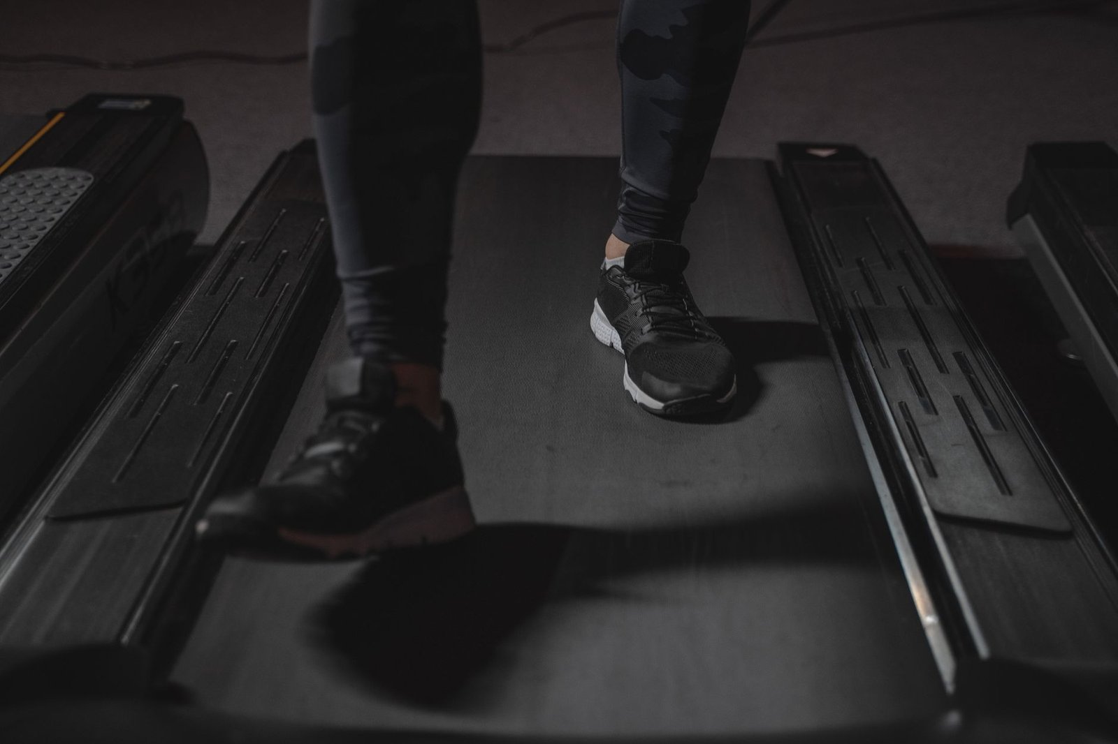 Compact walking pad neatly positioned under a modern ergonomic standing desk.