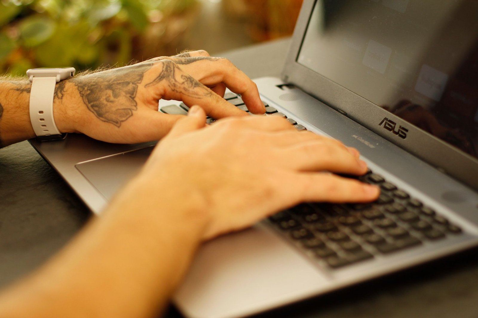 A focused professional working on a laptop at a wooden table.